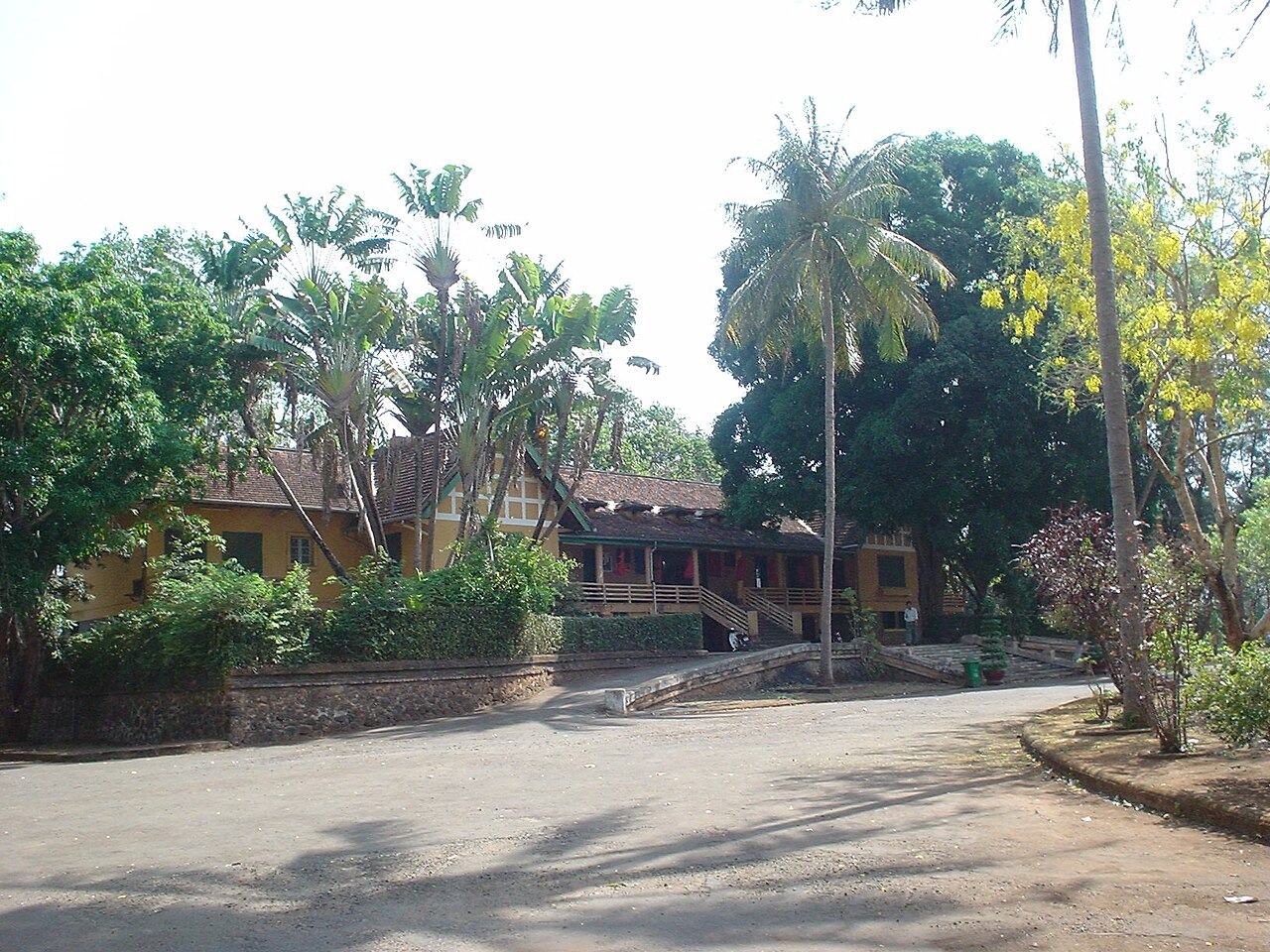 Yellow villa with a tiled roof and palms, seen from the side road at Bao Dai Palace