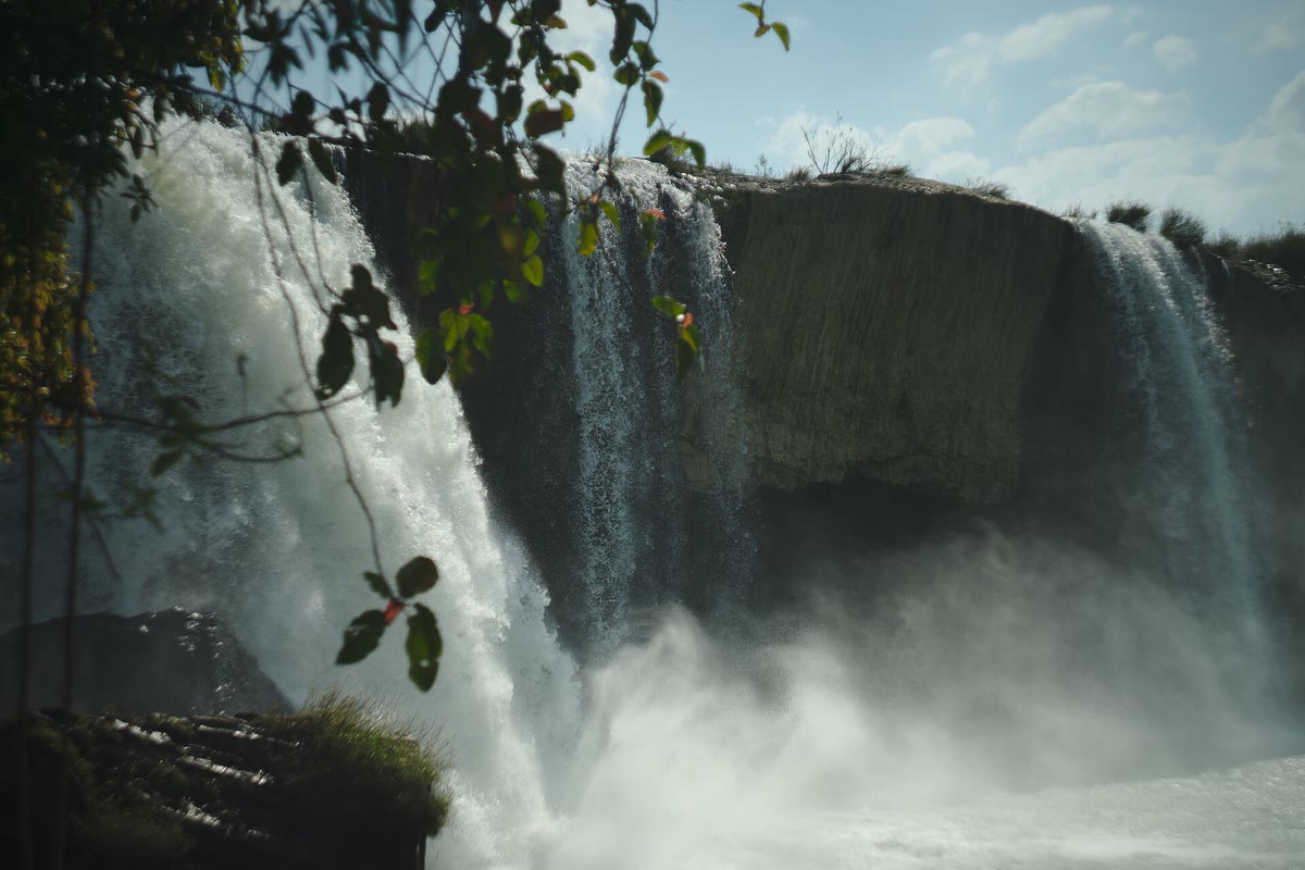 Water pouring over the Dray Nur cliff, with leaves in front and mist below