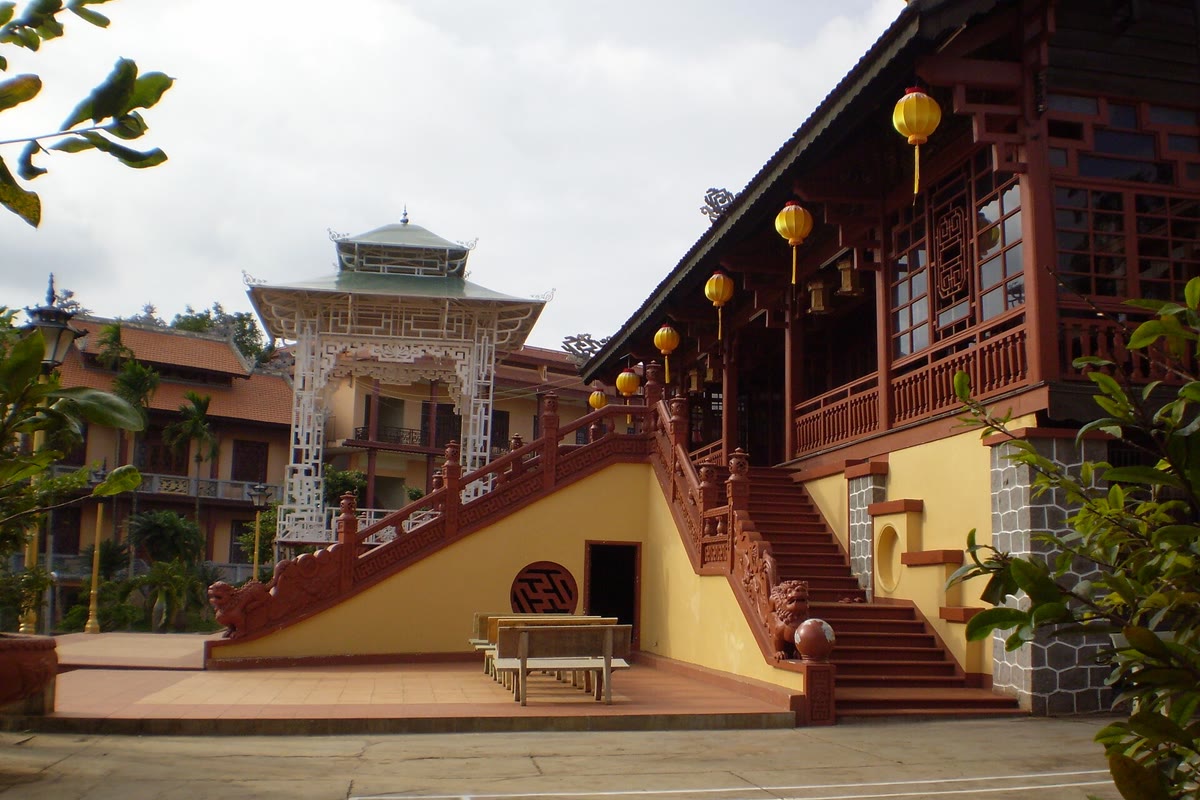 Carved stair and yellow lanterns at Khai Doan Pagoda, with a white pavilion in the courtyard