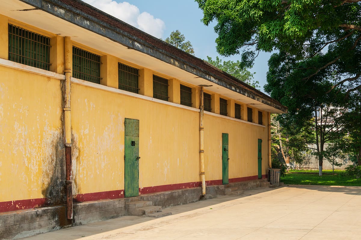 Yellow cell block with green doors and barred windows at Buon Ma Thuot Prison
