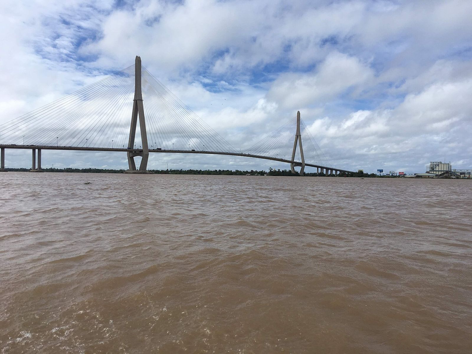 Both towers and the main span over the brown water of the Hậu