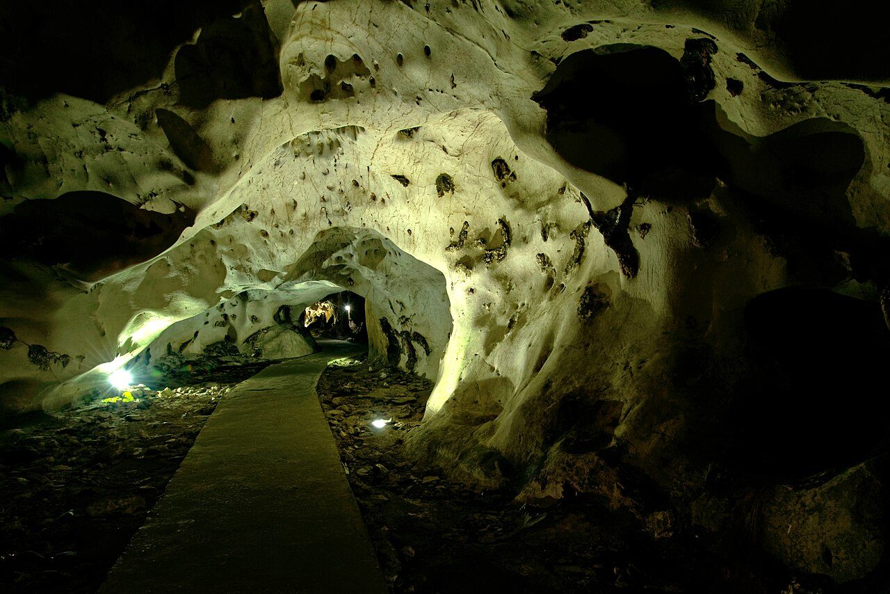 Lit limestone formations and a concrete path inside Trung Trang Cave