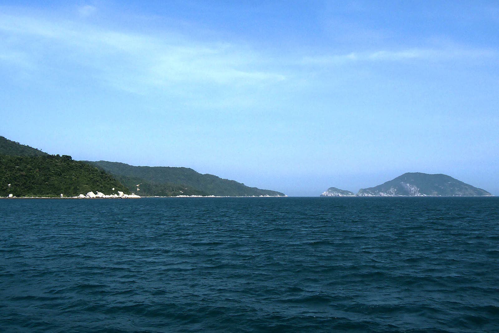 A forested island shore and smaller green islets across the water at Cu Lao Cham