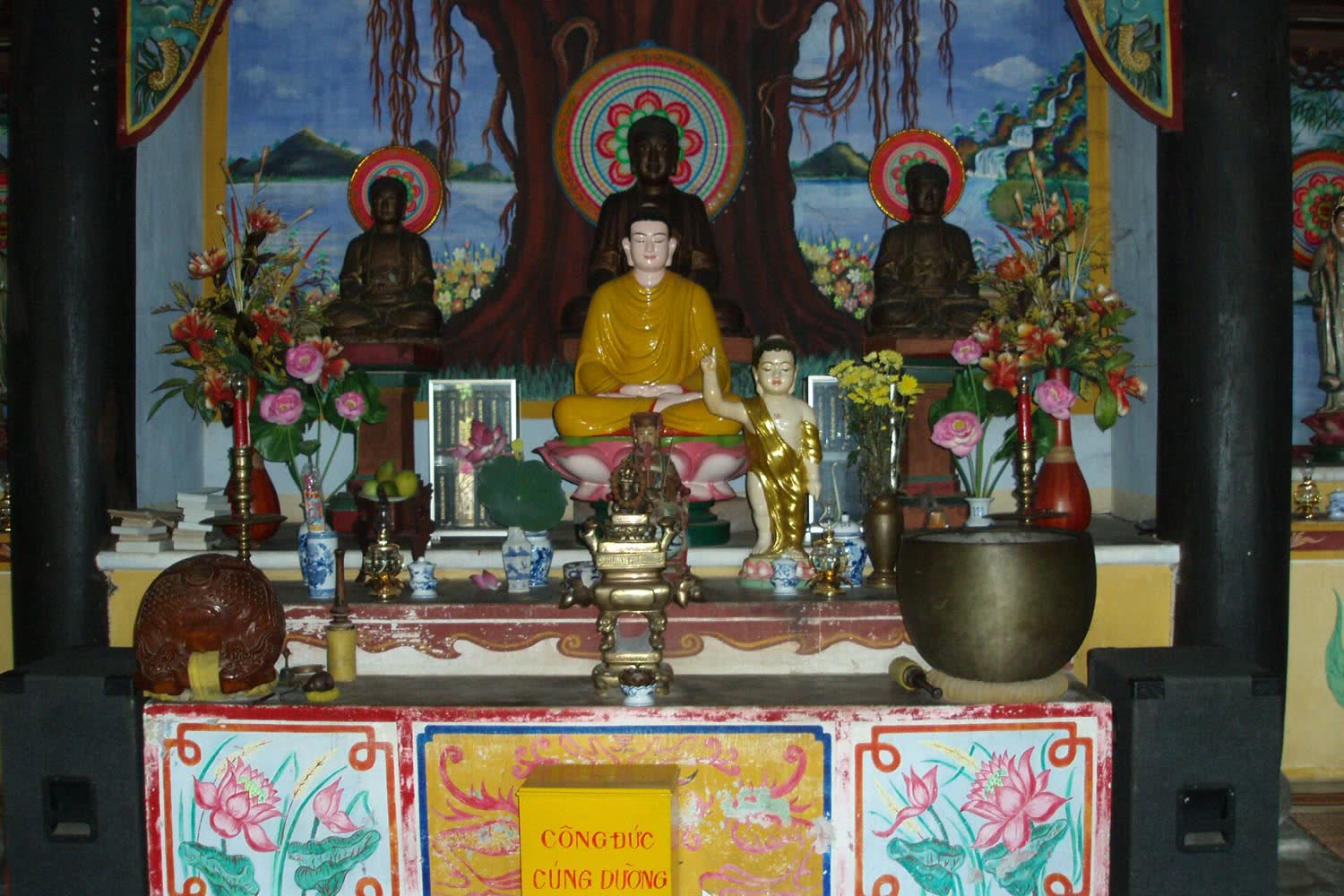 Seated Buddha statues and offerings in the main hall of Hai Tang Pagoda