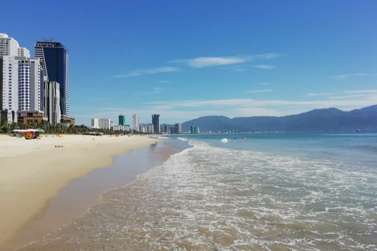 Surf and sand at My Khe, with resort towers along the left of the frame