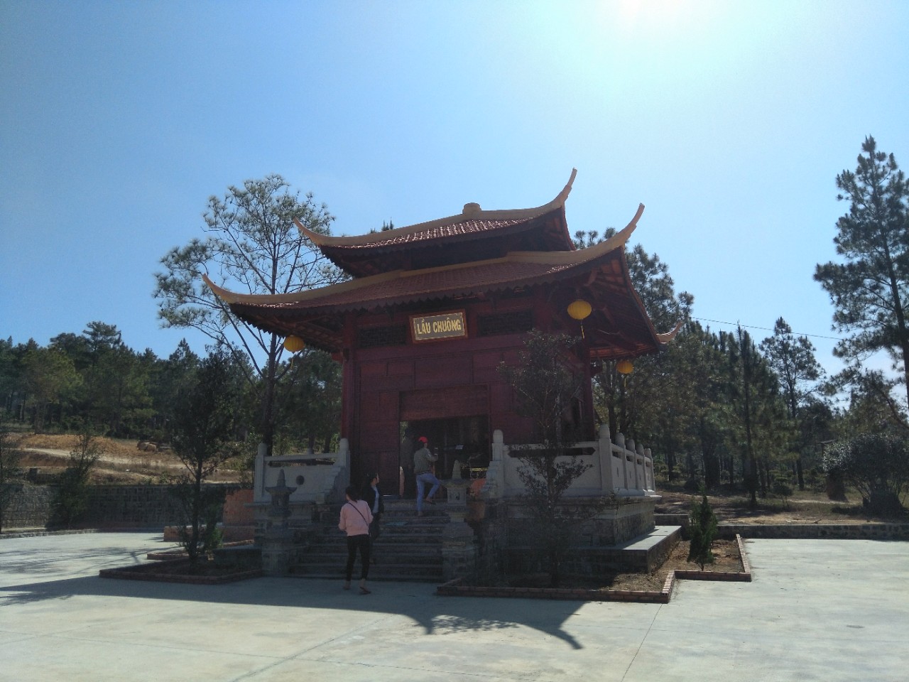 The red bell tower of Truc Lam Dao Nguyen, set among pine trees