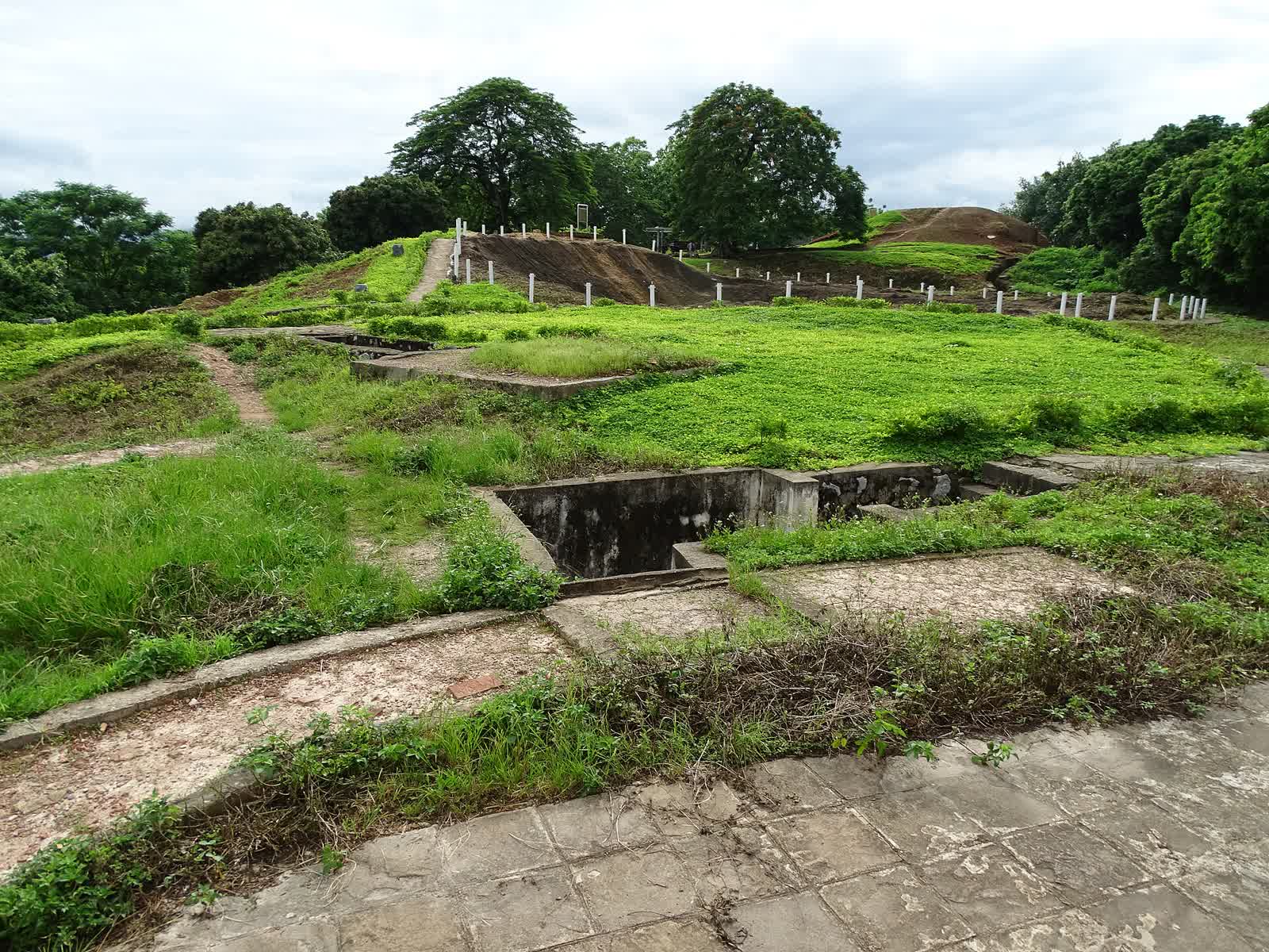Concrete trenches on the grassy slope of Hill A1, with the crater posts on the crest