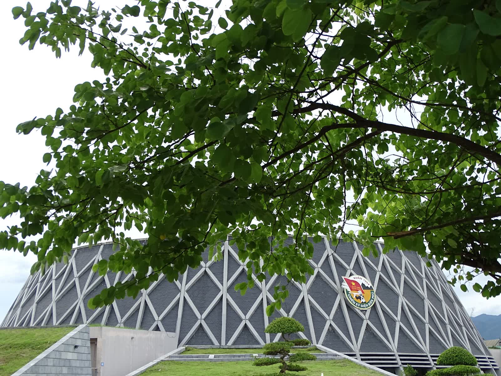The lattice facade of the Dien Bien Phu Victory Museum seen through trees