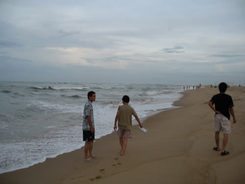 People on Nhật Lệ Beach with the surf in front of them