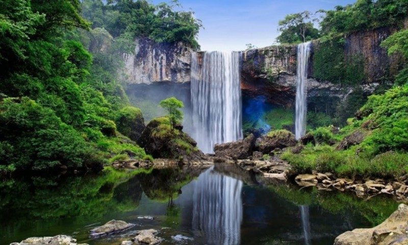 Cliff waterfall of K50 reflected in a dark pool, with forest on both banks
