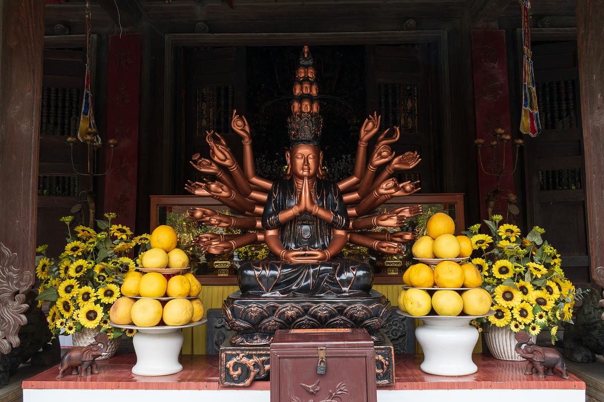 A thousand-armed figure seated in the hall at Du Hang pagoda, with fruit and flowers