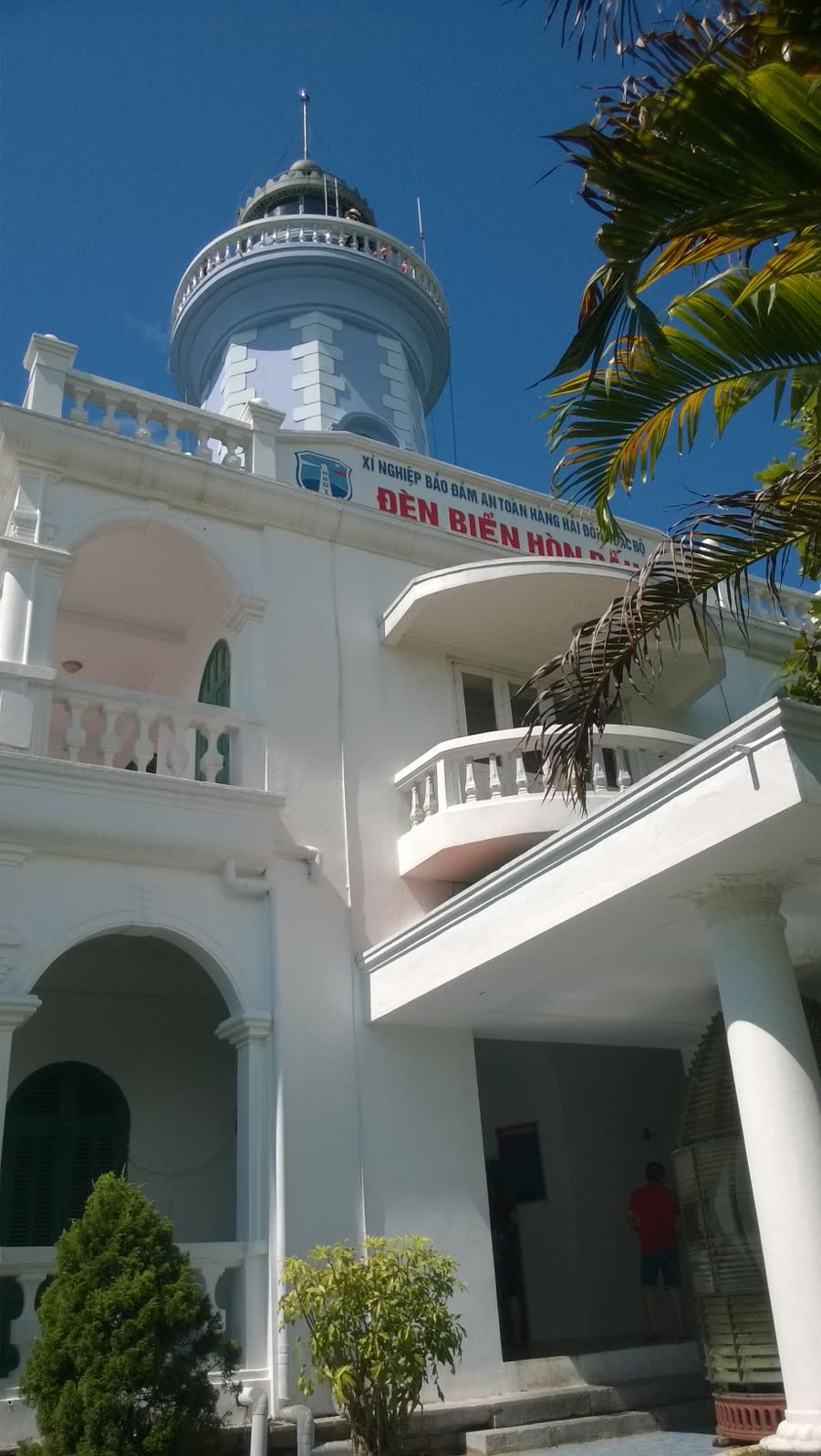 The white Hòn Dấu lighthouse with a blue lantern room against a clear sky