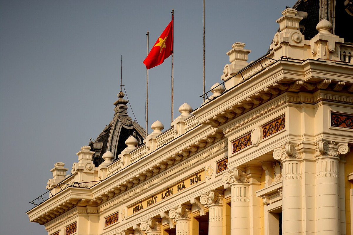 The ornate cornice of the Hanoi Opera House with the theatre's name and the national flag