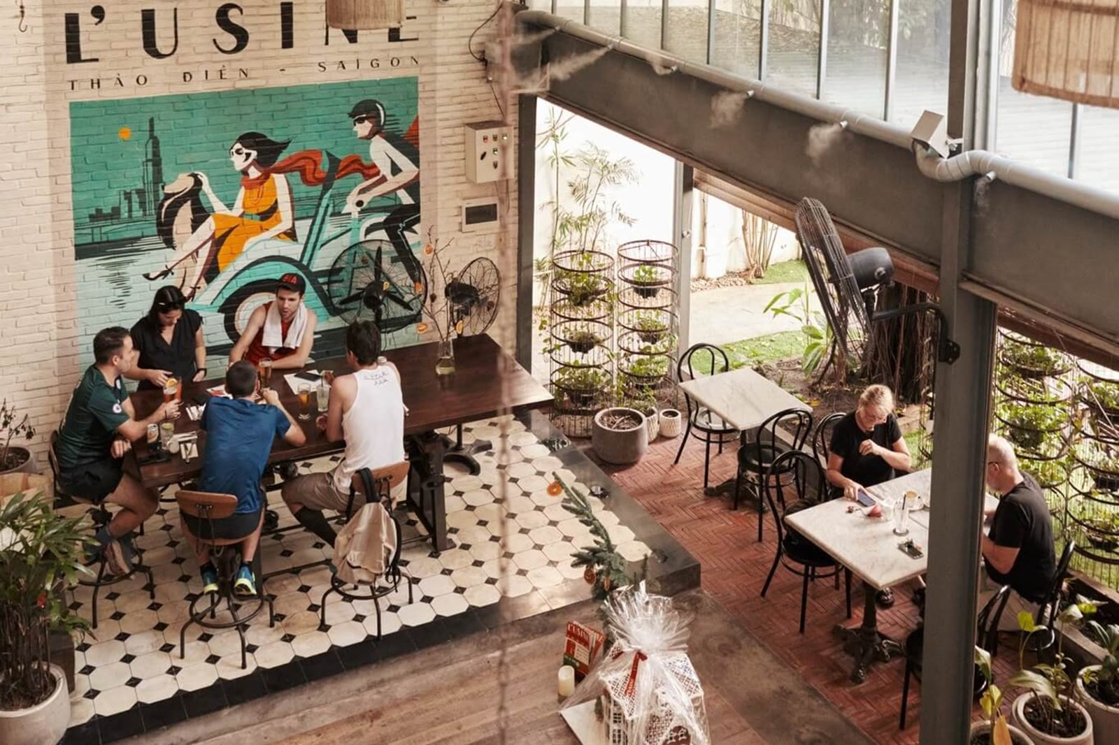 Cafe tables under a painted Saigon skyline mural in a high-ceiling brunch room