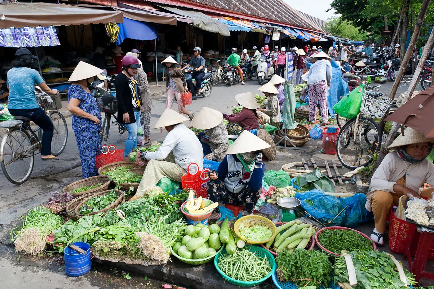 People selling baskets of herbs and vegetables at Hoi An Market