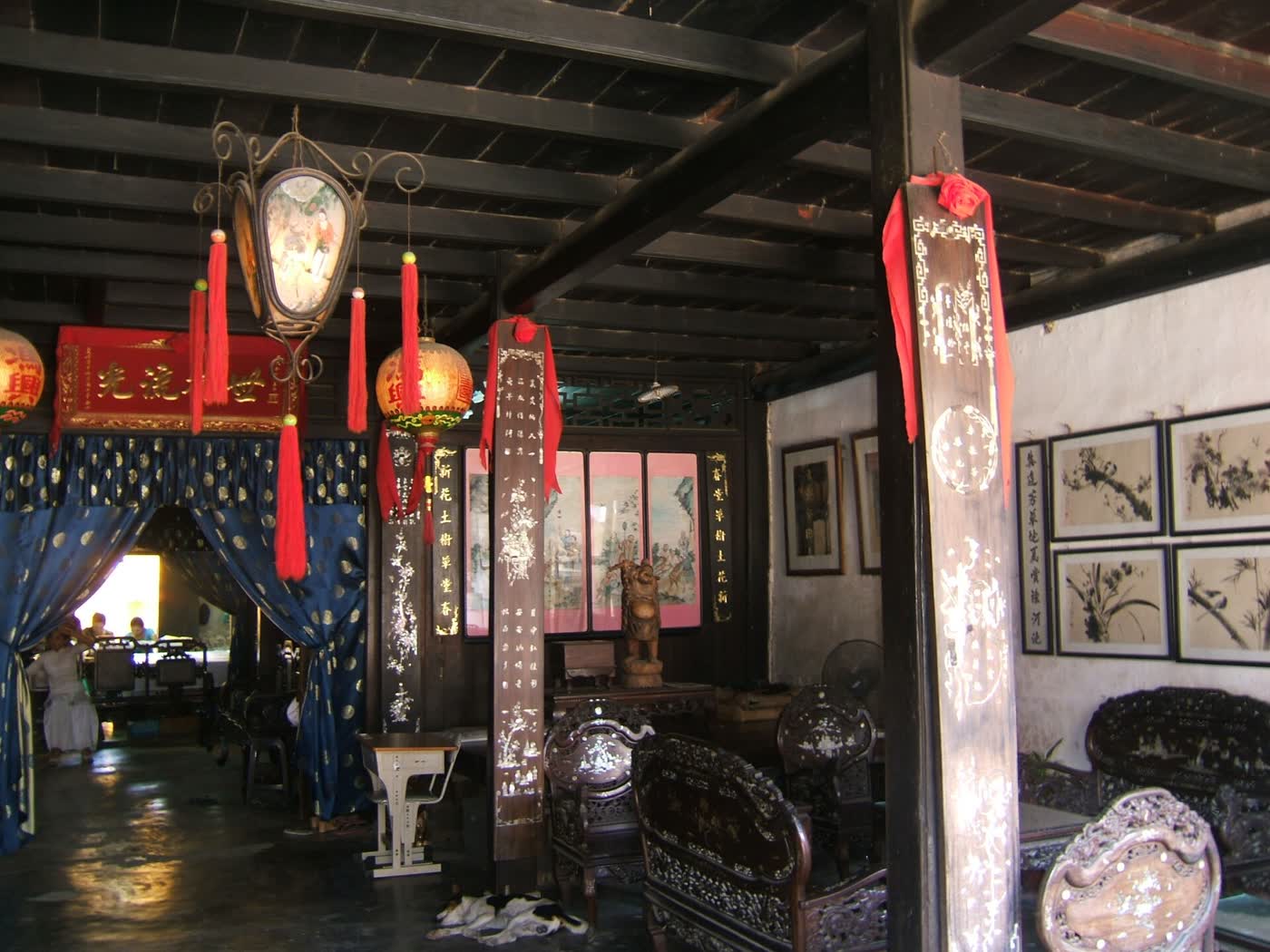 Dark wooden chairs and an inlaid column inside Phung Hung Old House in Hoi An