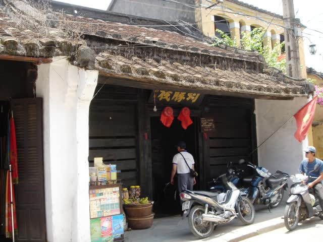 The tiled entrance of Quan Thang Old House in Hoi An, with the door open and motorbikes in front
