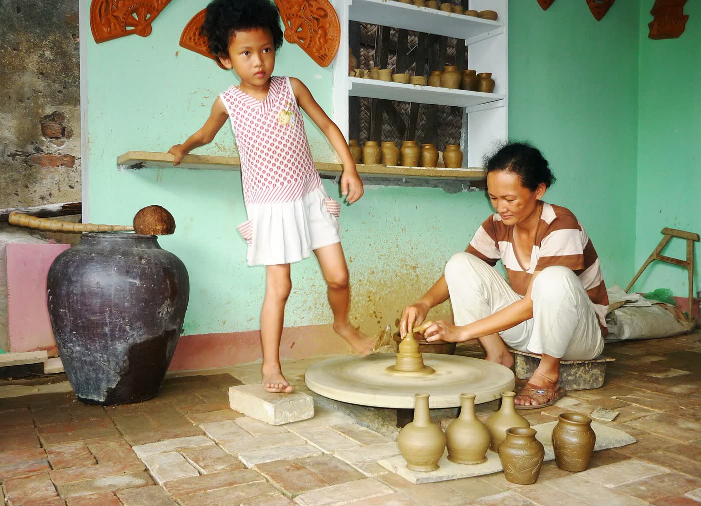 A potter at the wheel in Thanh Hà, with jars on the floor