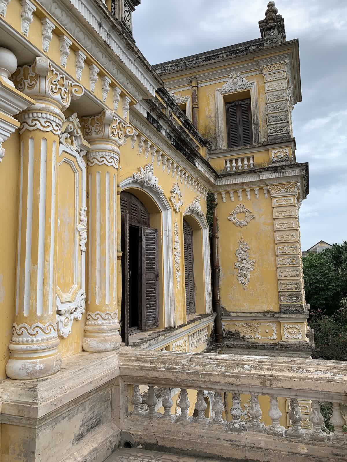 Carved stucco and columns on the yellow front of An Dinh Palace