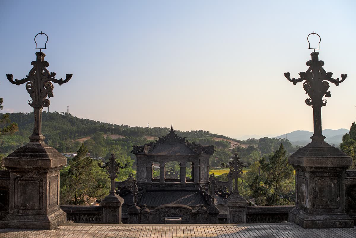 Ornate stone terrace and a small roof at Khai Dinh’s tomb, with hills and a wide sky behind