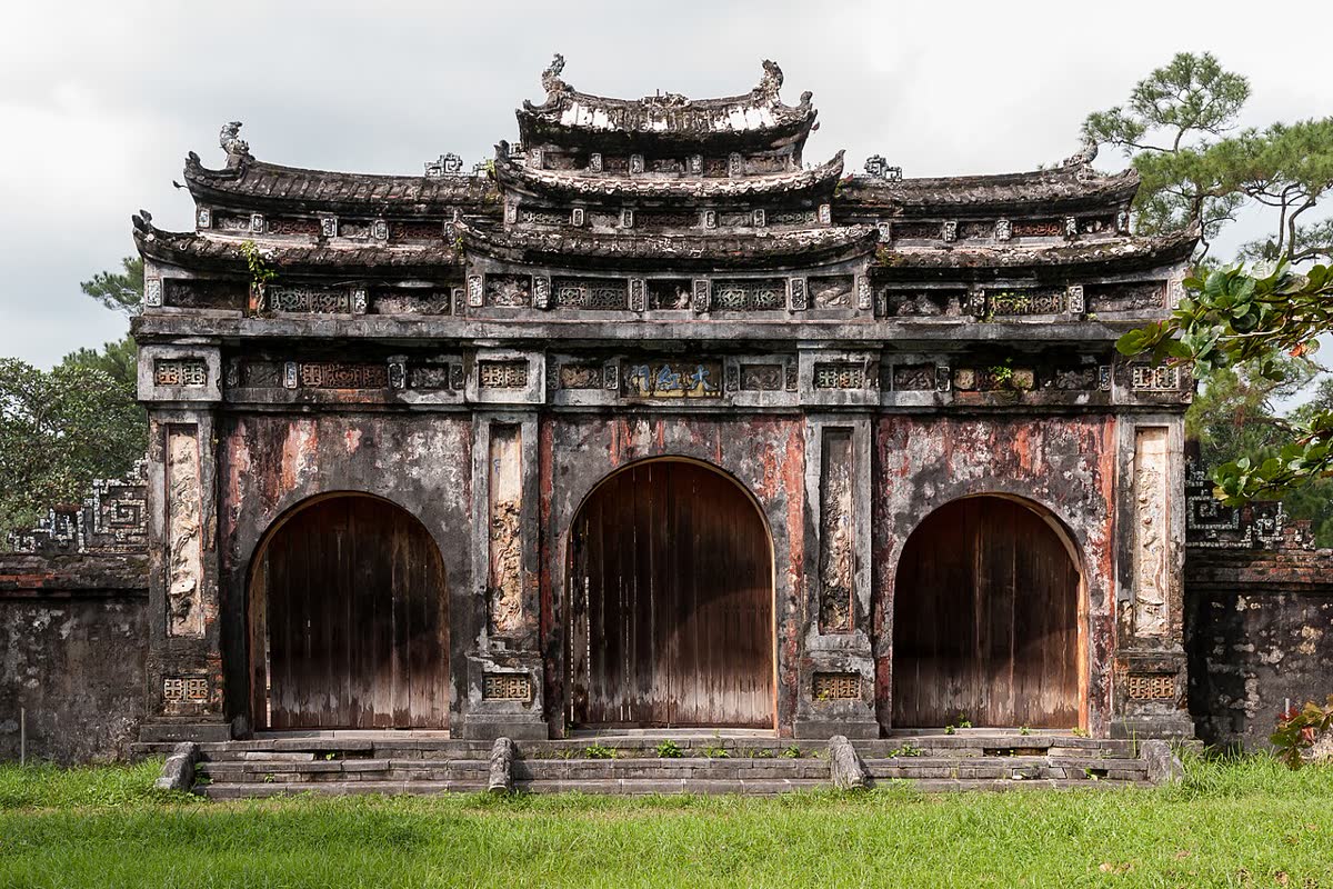 A weathered three-arch stone gate at the tomb of Minh Mang in Hue