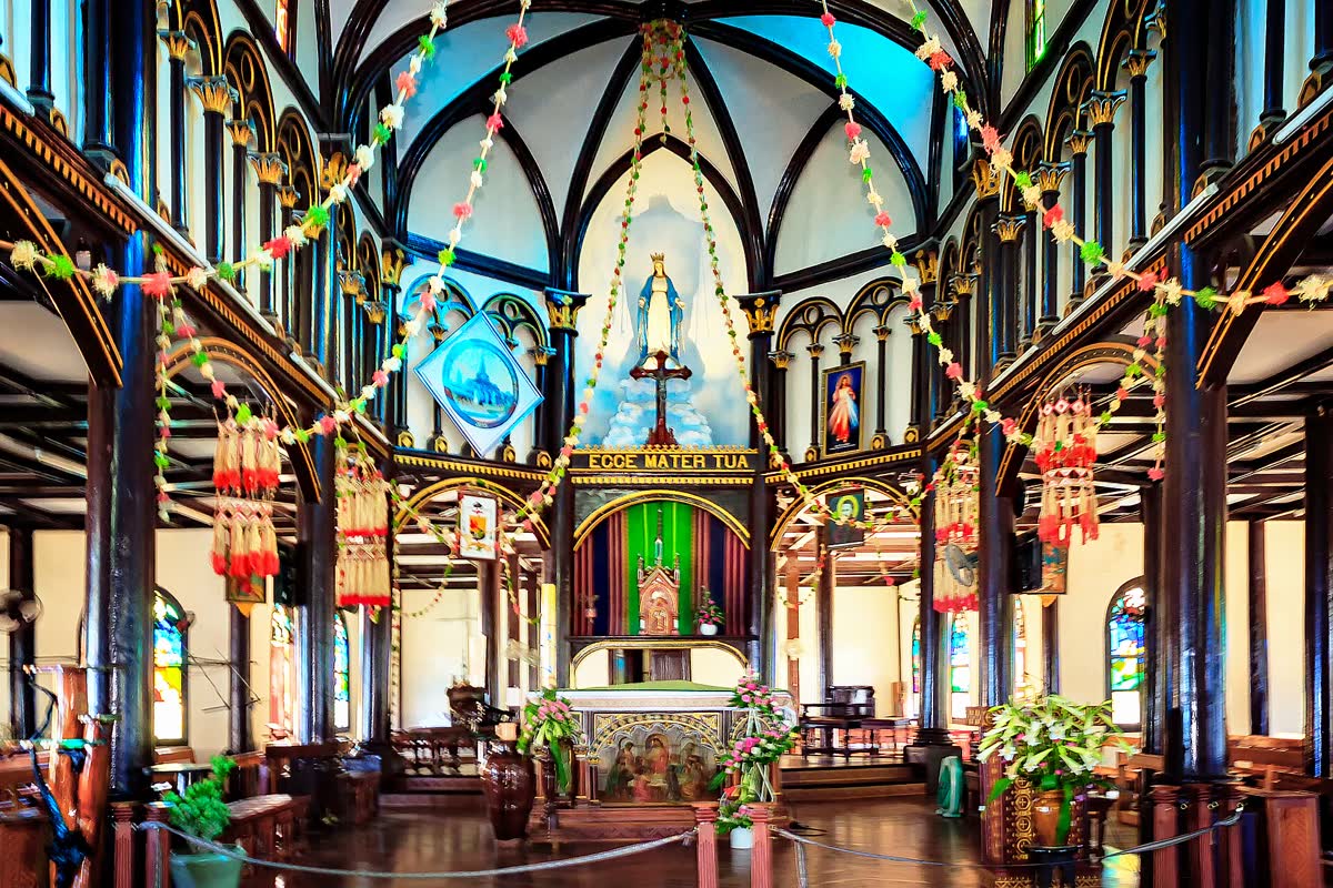 Timber columns, stained glass, and the sanctuary inside Kon Tum Wooden Church