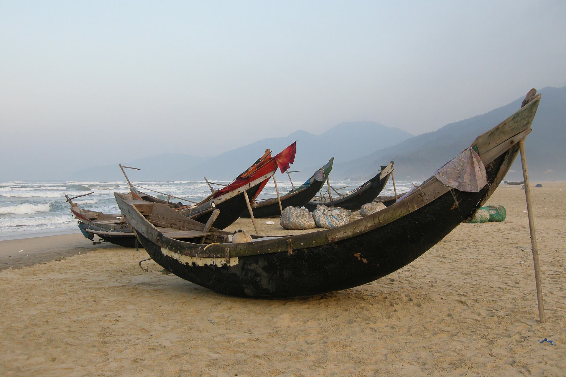 Fishing boats on the sand, with the ridge behind the surf