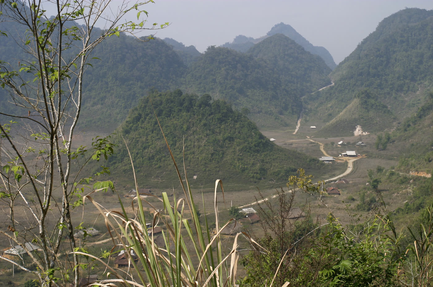 A highland road and scattered houses below forested ridges at Hang Kia