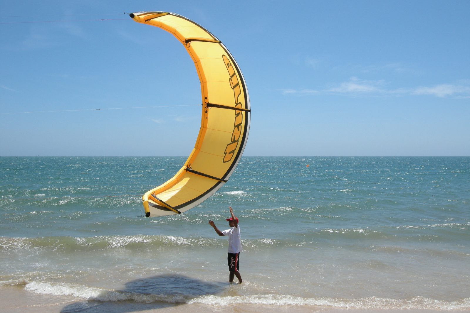 A kitesurfer holding a yellow kite above the water at Mui Ne beach