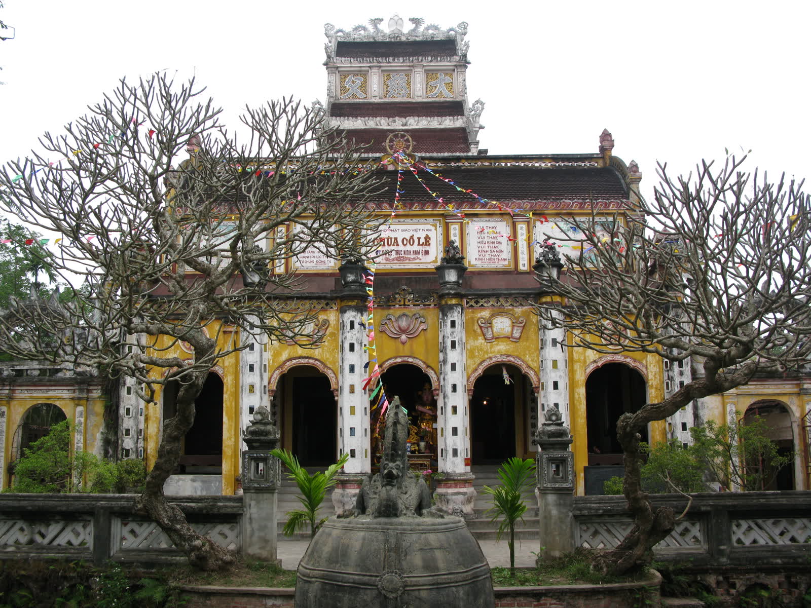The yellow hall of Co Le pagoda, with a bell in the court and bare trees in front