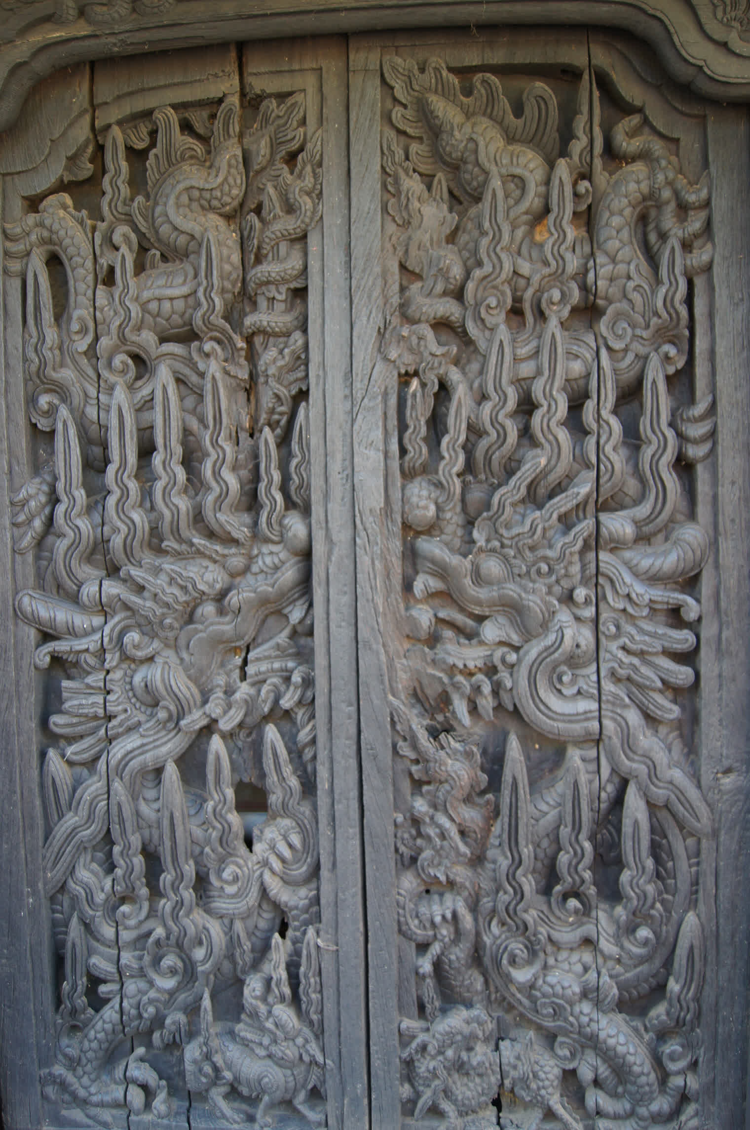 Dark wooden doors carved with dragons at the Tran temple in Nam Dinh