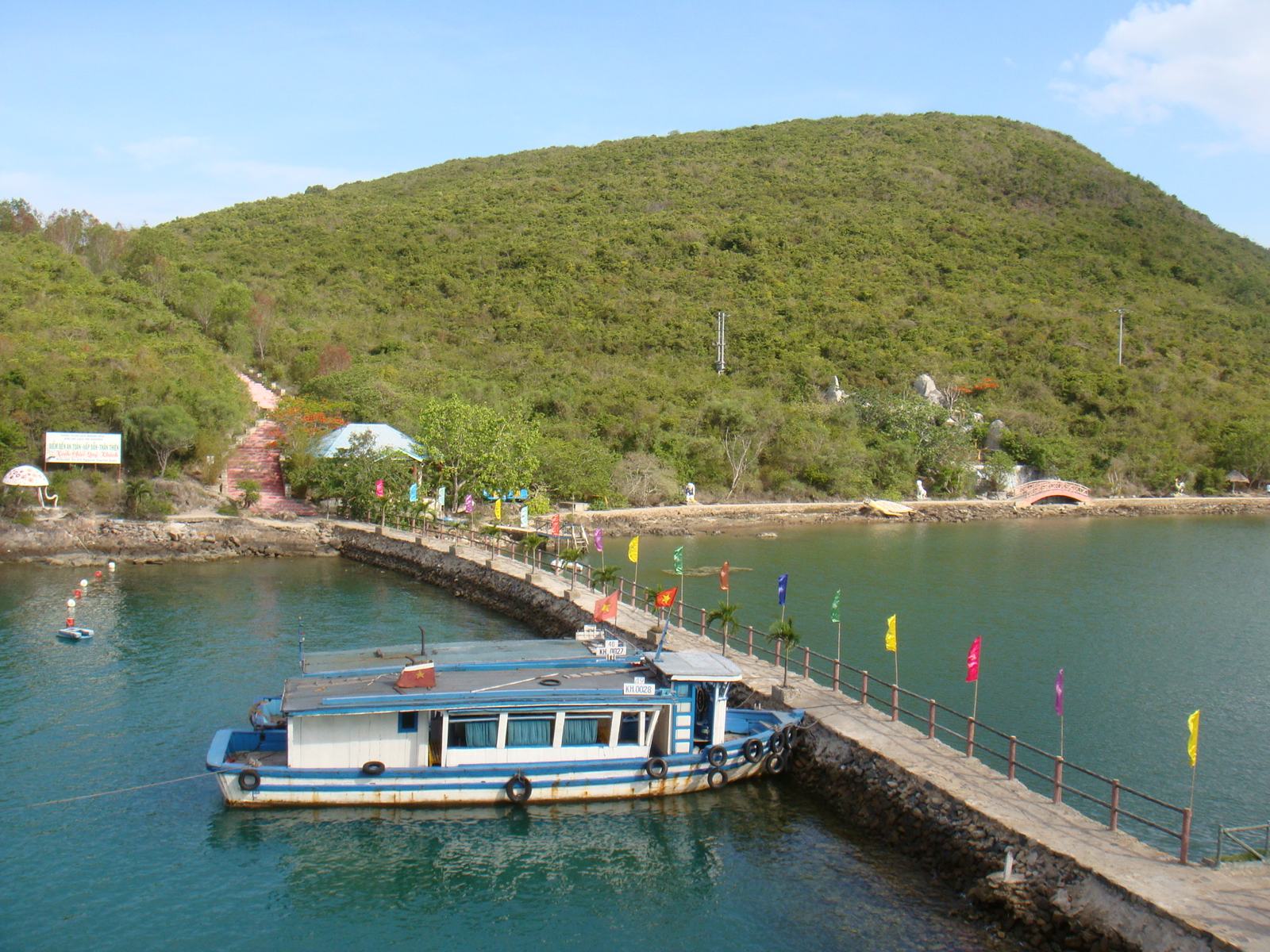 A blue tour boat at the stone pier on the aquarium island in Nha Trang Bay