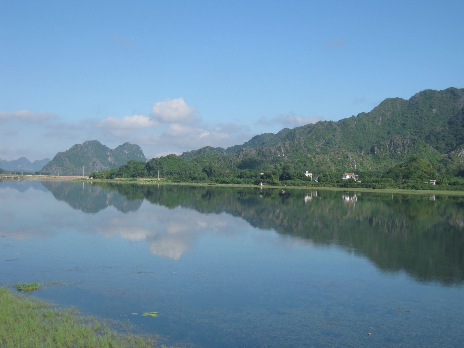 A calm lake reflecting limestone mountains at Dong Hoa Lu