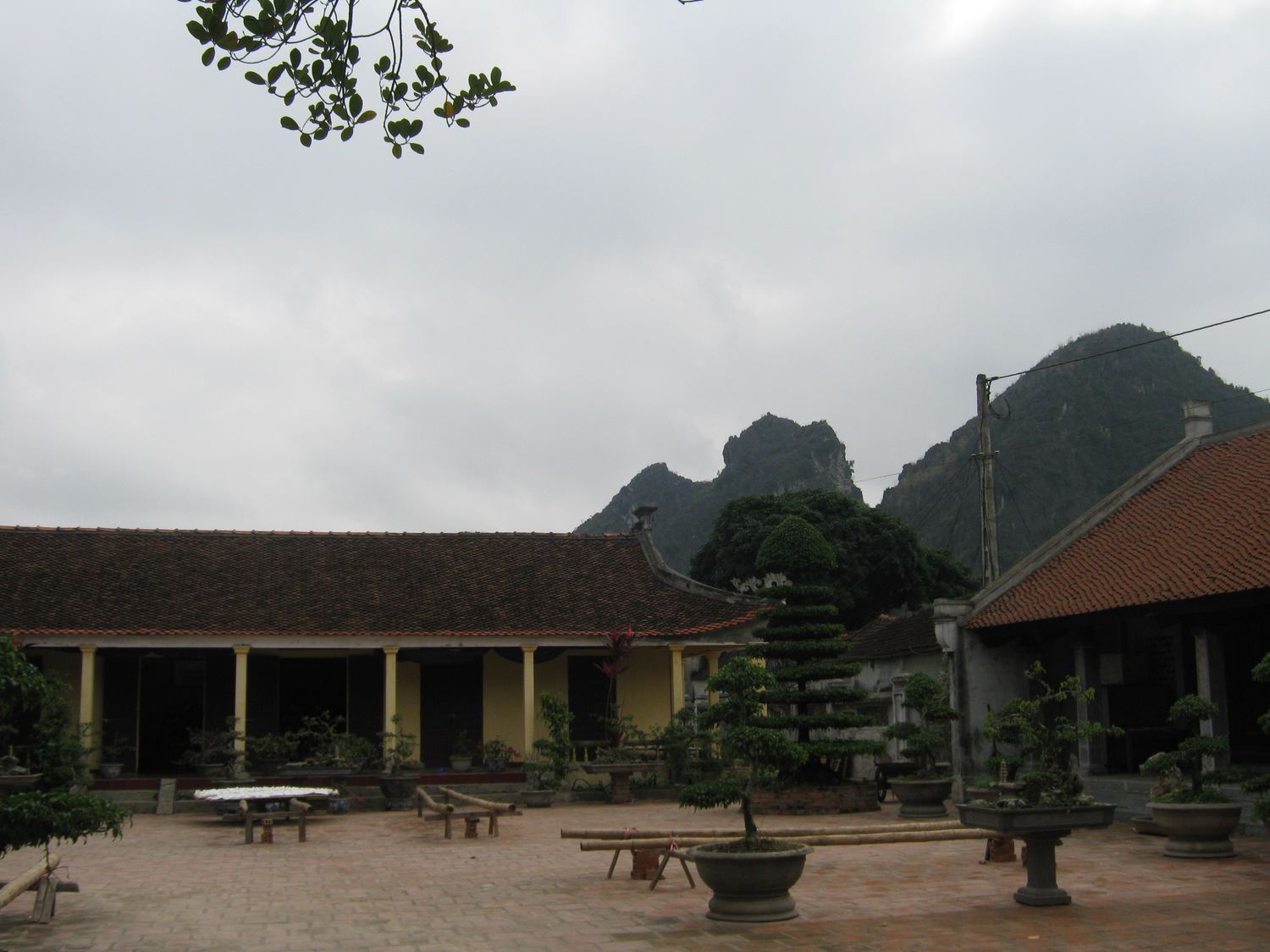 The tiled court and wooden hall of Nhat Tru Pagoda, with a limestone peak behind