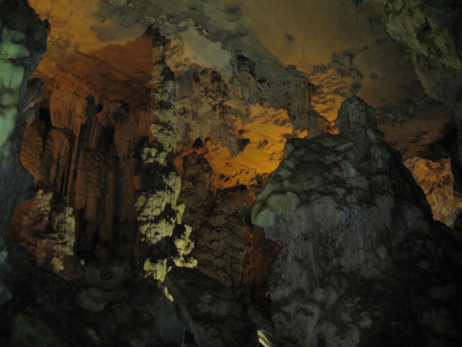 Orange-lit stalactites and a rock mass inside Van Trinh Cave