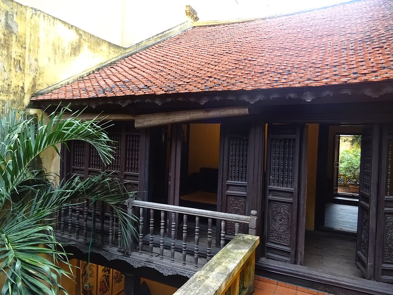 A carved wooden gallery and red tiled roof inside the heritage house at 87 Ma May