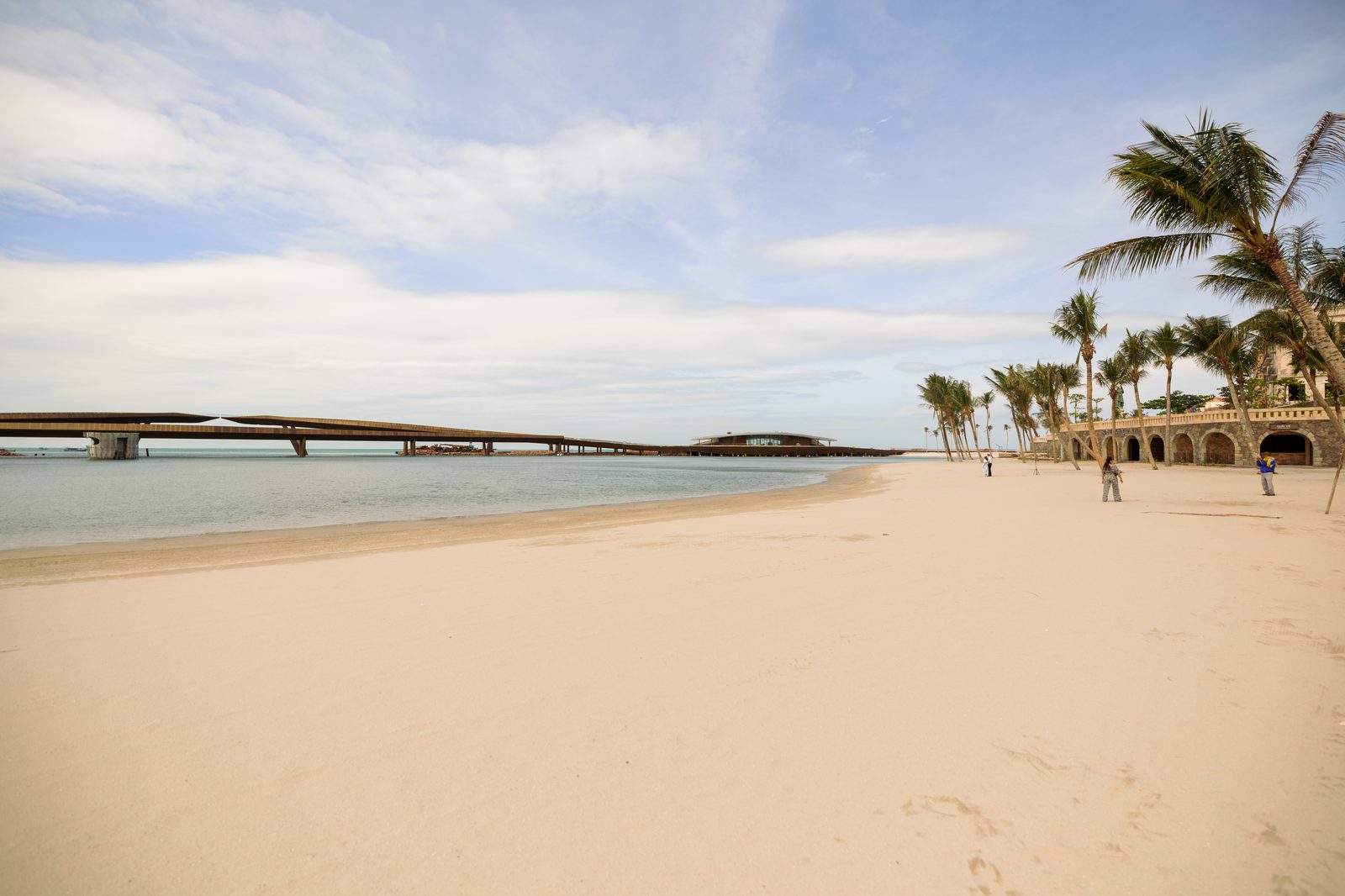Kiss Bridge stretching over the water beside a palm beach at Sunset Town