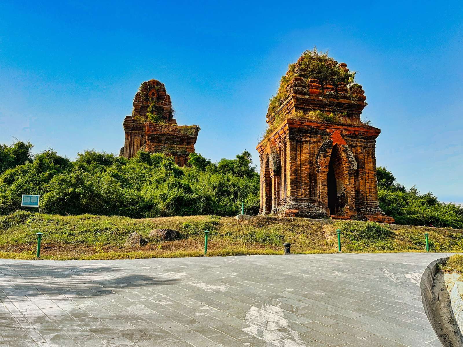 Two brick Cham towers of Tháp Bánh Ít above a paved forecourt