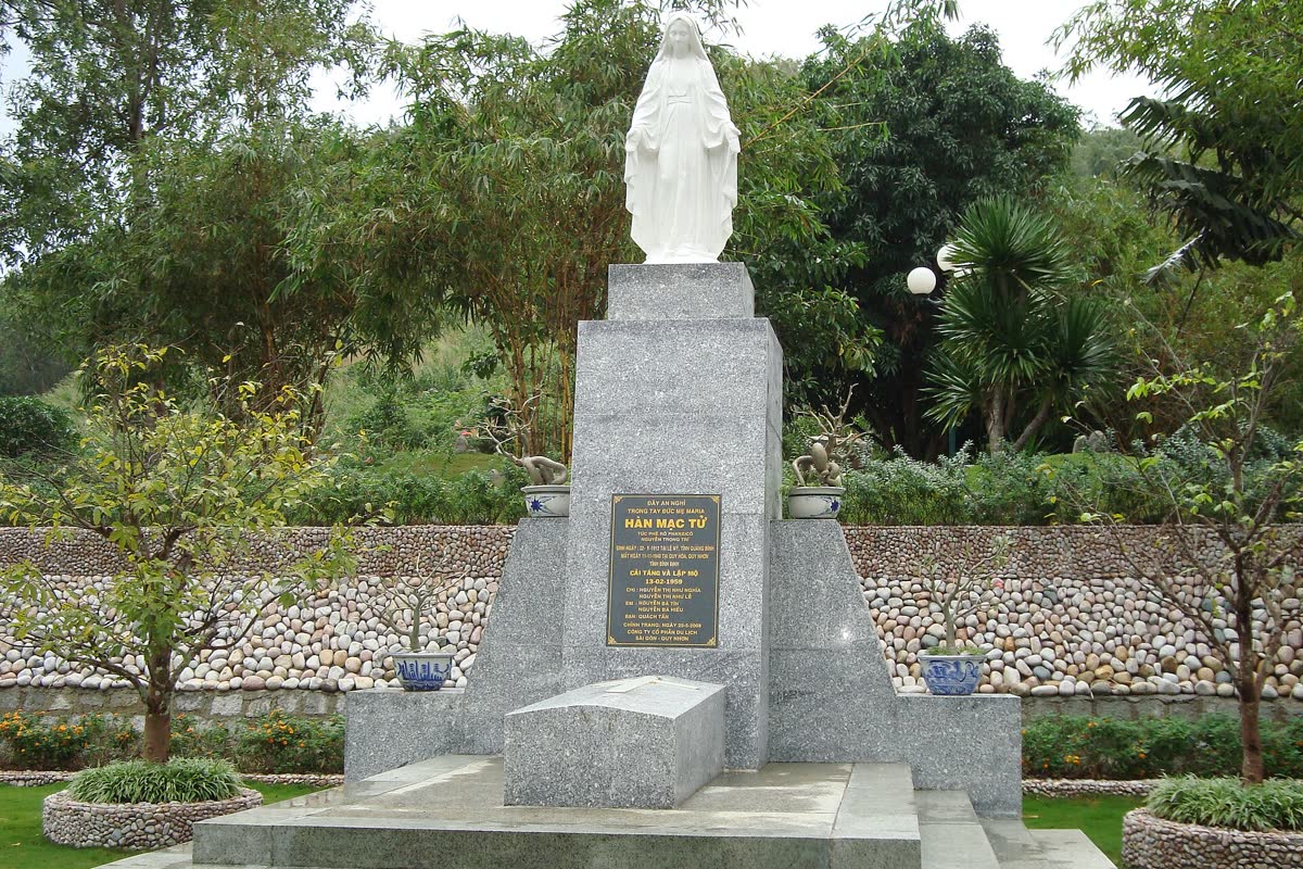 The white figure of Hàn Mặc Tử on a stone pedestal above the grave at Ghềnh Ráng