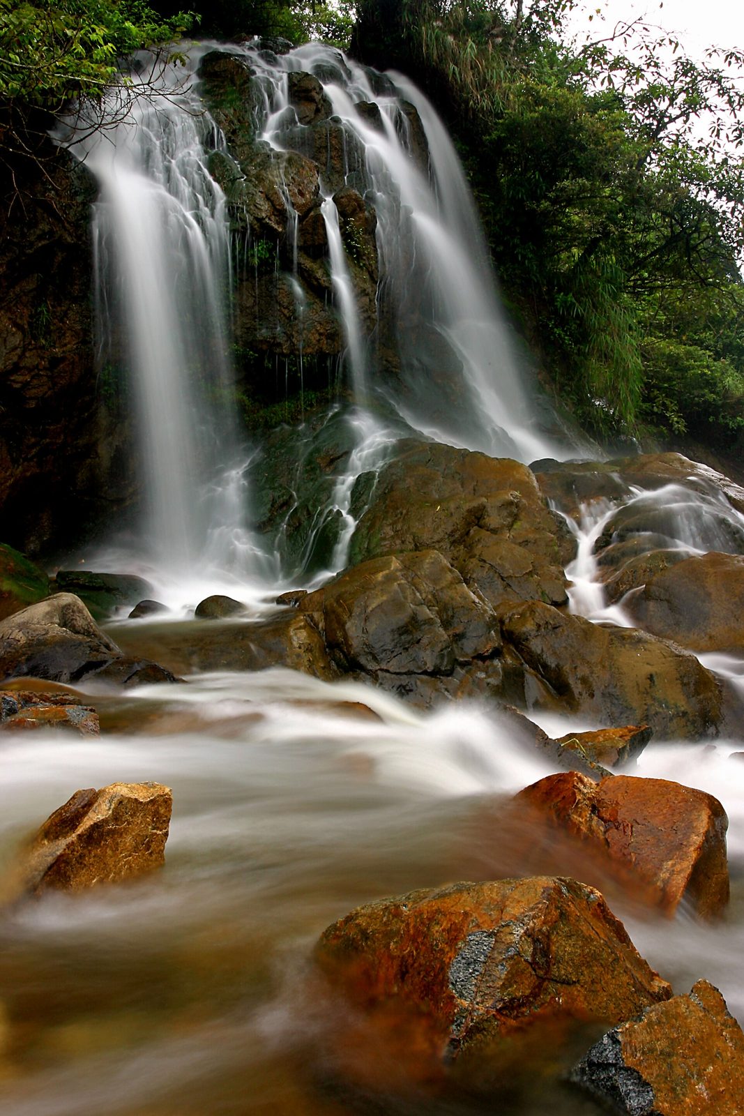 Cat Cat waterfall pouring over dark rocks into a rocky stream