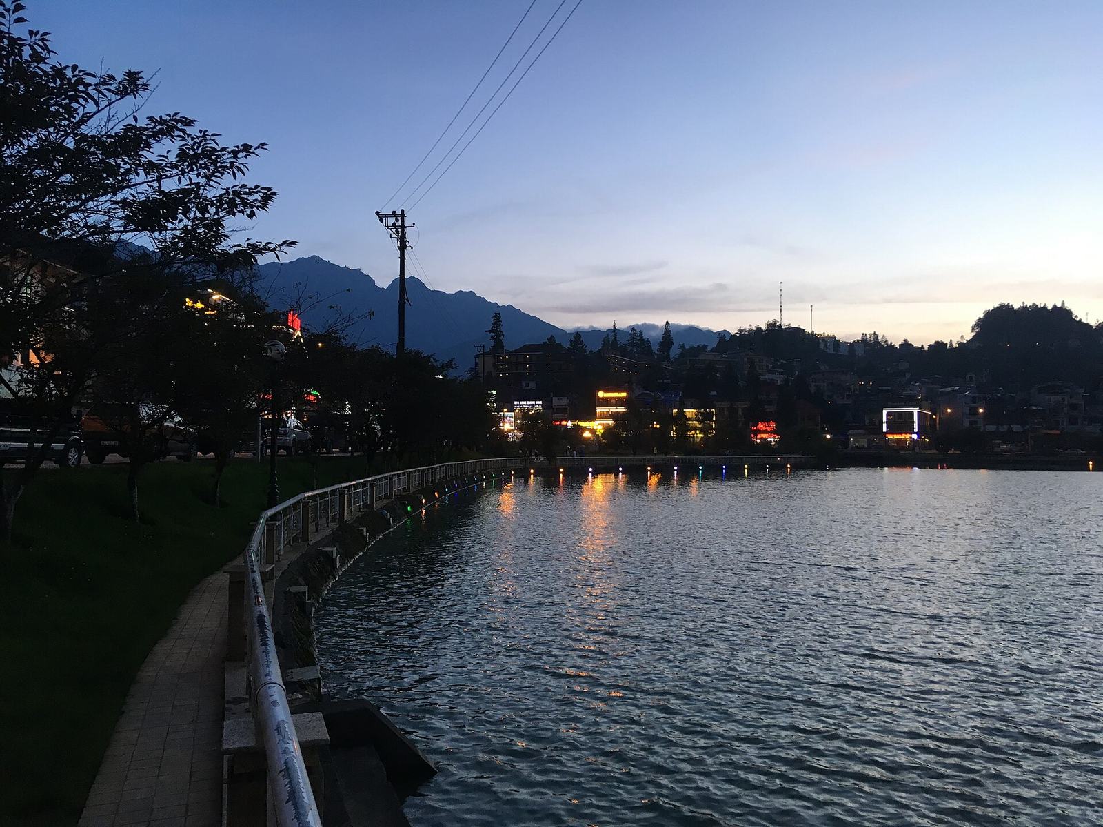 Sa Pa Lake at dusk with lights reflecting on the water and the town hill behind