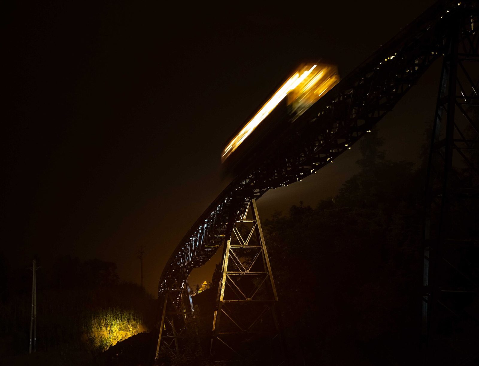 A lit mountain train crossing a steel viaduct at night in Sa Pa
