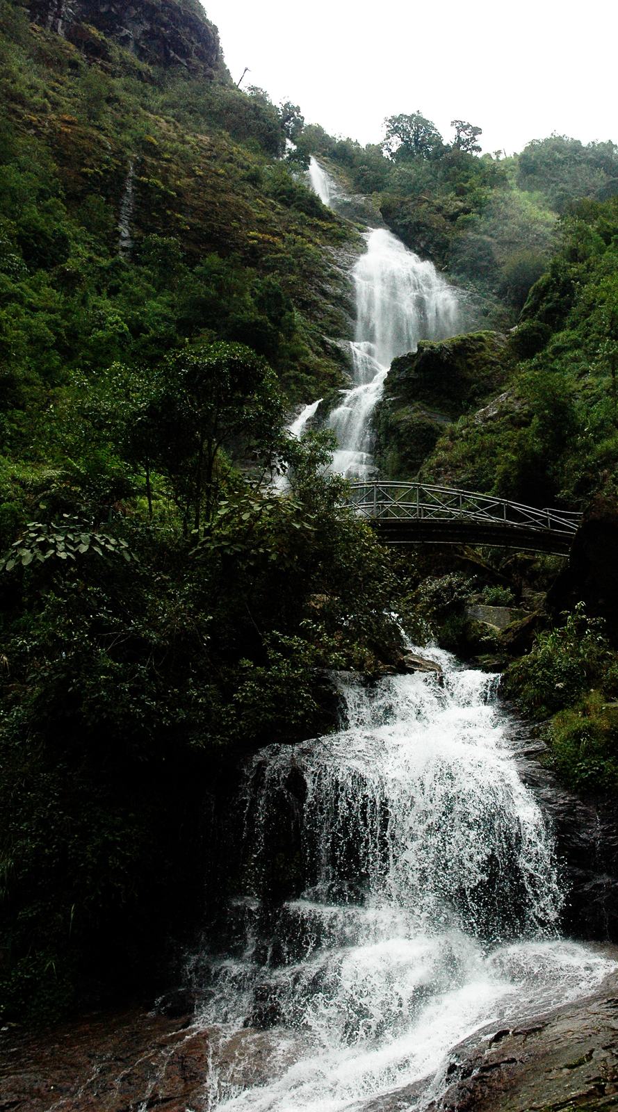 Silver Waterfall dropping past a footbridge into a rocky stream