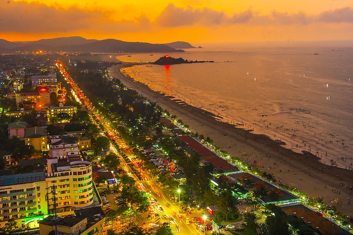 Dusk over Cua Lo beach, the long sand, the tree-lined road, and an island offshore