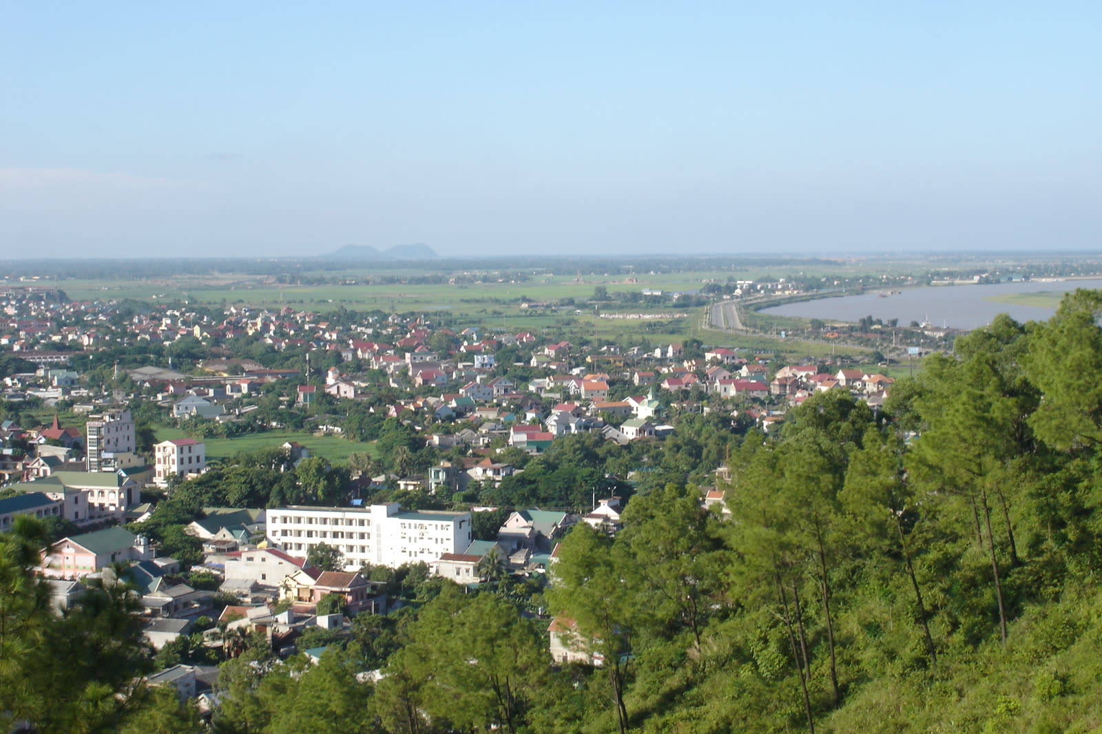 The city of Vinh and the Lam River seen from Quyet Mountain, with pines in the foreground