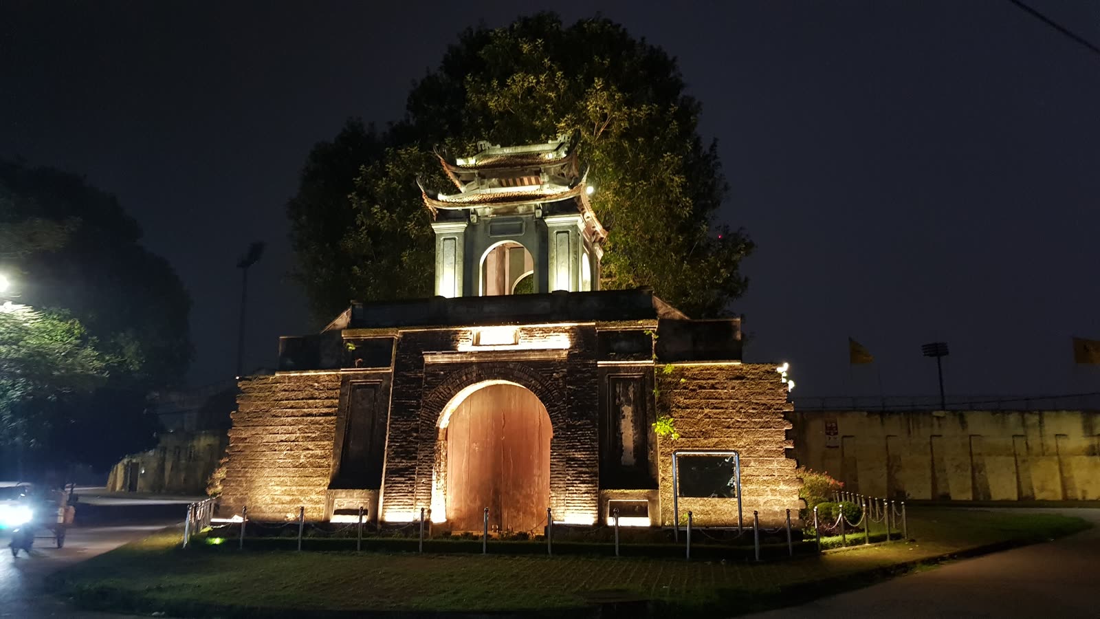 The Vinh citadel gate lit at night, with the wooden doors and the pavilion above